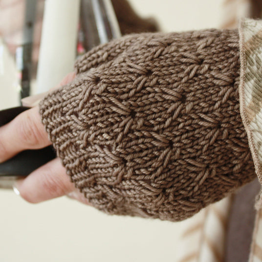 A close up of a woman's hand, wearing a knitted fingerless mitt.