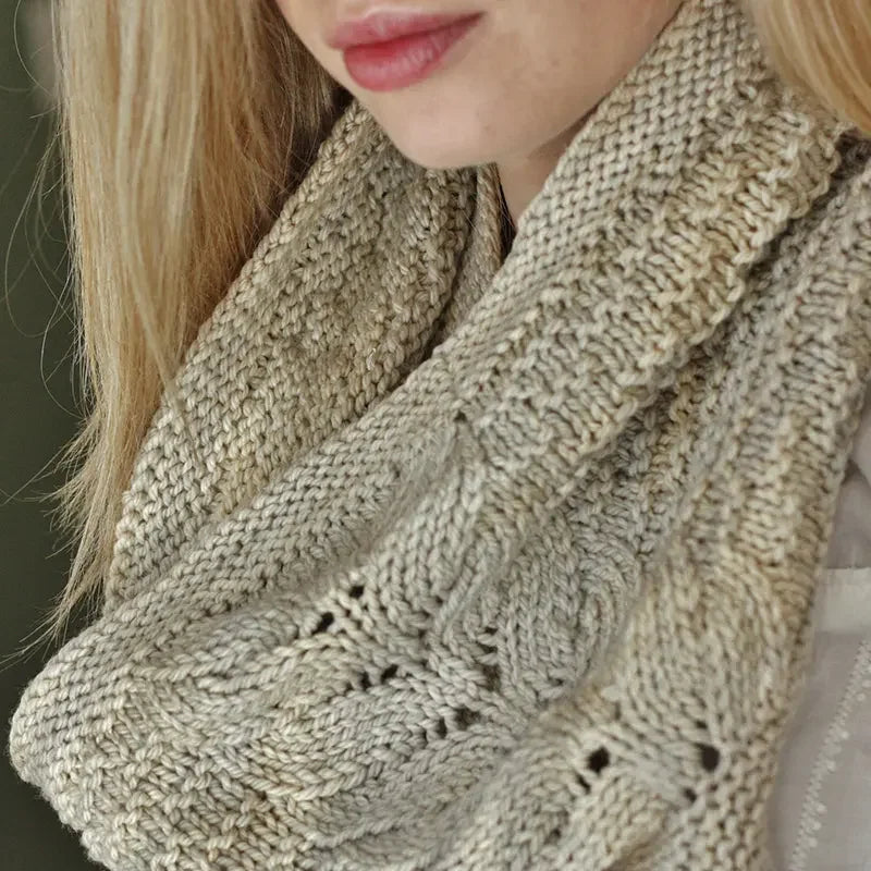 Close-up of a woman wearing a hand-dyed, cream cable-knit scarf from Augustbird