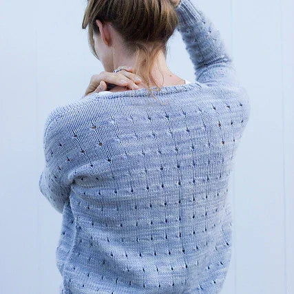 Woman wearing a soft hand-dyed light blue knit sweater with a dotted pattern, shown from the back
