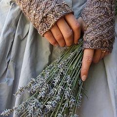 Hands wearing hand-dyed brown textured fingerless gloves holding a bundle of lavender flowers