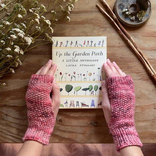 Two hands wearing fingerless mitts holding a book.