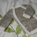 Baby frontless cardi on a quilt with a leaf pattern.