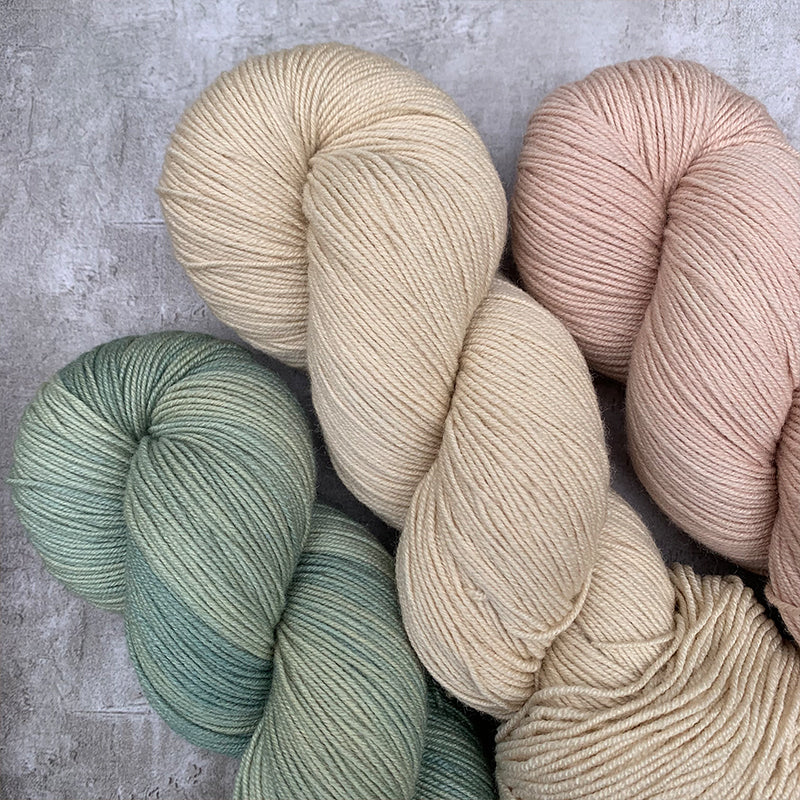 Three skeins of hand dyed yarn. From left to right, pale blue, tea dyed then light pink.