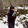 Woman standing in the snow, wearing winter clothes and fingerless mitts