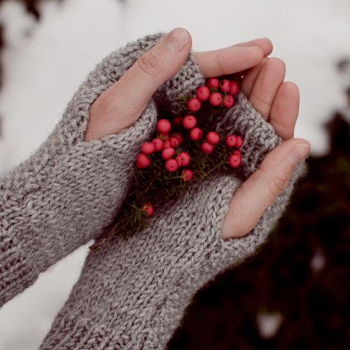 Close up of hands wearing mitts, with a handful of red berries